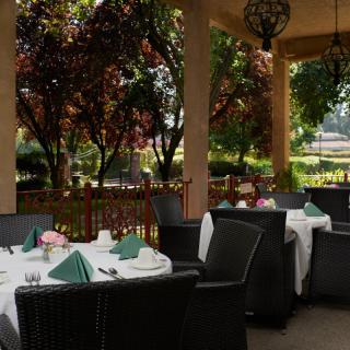 An inviting outdoor dining area with neatly set tables surrounded by lush greenery.