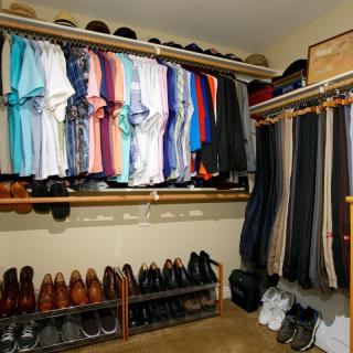A neatly organized closet with shirts, trousers, and shoes displayed on shelves and hangers.