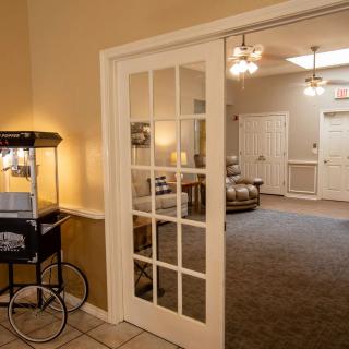 A cozy living room with a popcorn machine near French doors, leading to a carpeted area with warm lighting.