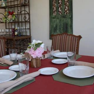 A dining table set with plates, glasses, napkins, and a floral centerpiece, ready for a meal.