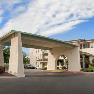 Exterior view of a hotel with a covered entrance and clear skies above.