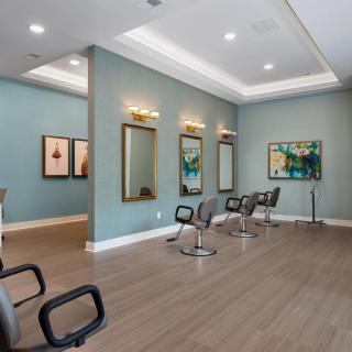 A modern hair salon interior with stylish chairs, mirrors, and artwork.