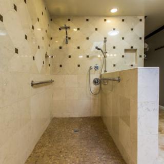 A modern, accessible walk-in shower with grab bars and stylish tiling.