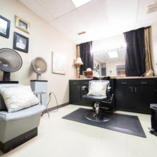 A cozy hair salon interior with chairs, a mirror, and hairdryers.