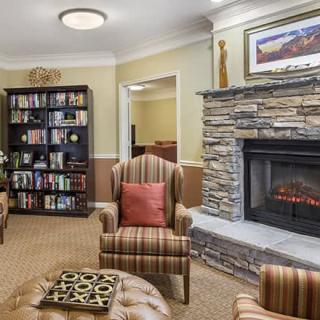 A cozy living room with a fireplace, armchairs, and a bookshelf filled with books.
