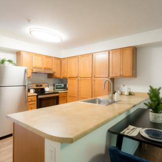 A modern kitchen with wooden cabinets, stainless steel appliances, and a cozy dining area.