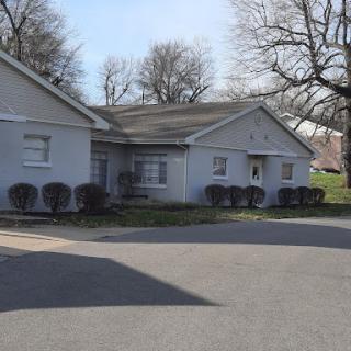 A quiet residential building surrounded by trees on a sunny day.