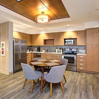 A modern kitchen with wood cabinetry, a round dining table, and contemporary appliances.