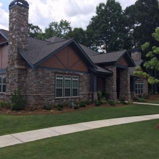 A charming stone house with a well-maintained lawn and pathway.