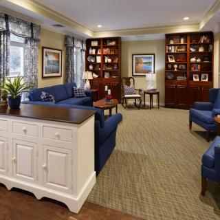 A cozy living room featuring blue sofas, bookshelves, and elegant decor.
