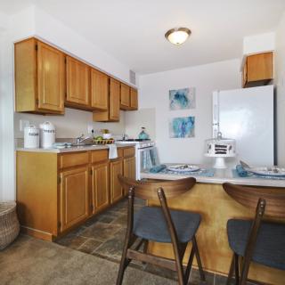 A cozy kitchen and dining area with wooden cabinets and counter stools.