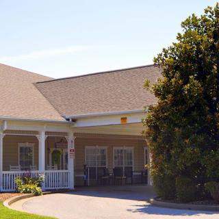 A suburban house with a porch and driveway surrounded by trees.