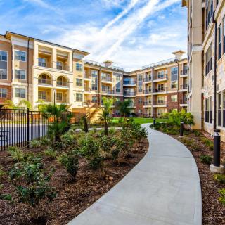Modern apartment complex with landscaped pathways and multi-story residential buildings.