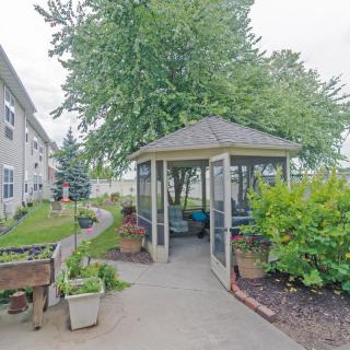 A serene garden area featuring a gazebo surrounded by lush greenery and a winding pathway.
