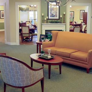 A cozy living room featuring a sofa, chairs, and a small coffee table, with warm lighting and elegant decor.