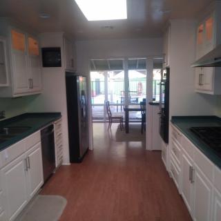 A modern kitchen with white cabinets and wood flooring, featuring a bright and open layout.