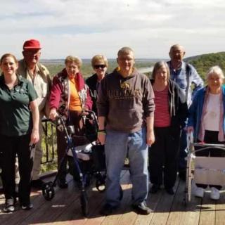 A group of people enjoying a sunny day outdoors, with some using mobility aids.