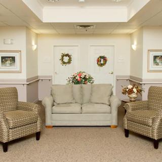 A cozy waiting room with a sofa, two armchairs, and decorative artwork on the walls.