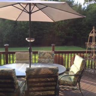A sunny backyard patio with a table, chairs, and an umbrella.