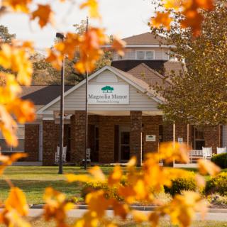 A building surrounded by colorful autumn leaves with a sign at the entrance.