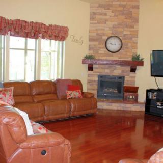 A cozy living room with leather sofas, a fireplace, and a TV on hardwood flooring.