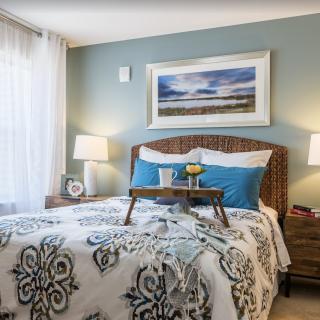 A cozy bedroom interior with decorative pillows, a patterned bedspread, and bedside lamps.