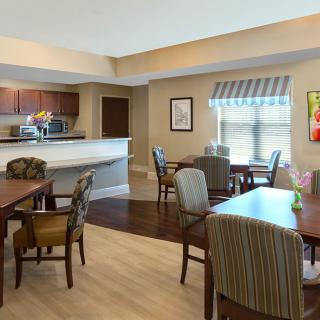 A cozy dining area with several tables and chairs, connected to a kitchen space.