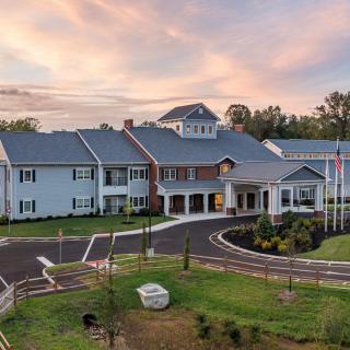 A large residential-style building with a landscaped driveway under a sunset sky.