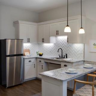 A modern kitchen with white cabinets, stainless steel appliances, and stylish pendant lights.