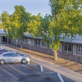 A school building with a parking lot and trees on a sunny day.