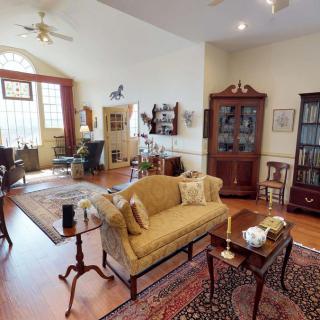 A traditionally styled living room with elegant furniture, featuring a sofa, coffee table, and bookshelves.