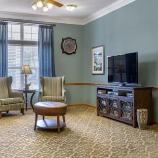 A cozy living room with comfortable chairs, a coffee table, and a television set.