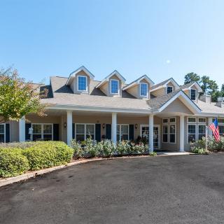 A suburban residential building with a neatly landscaped front area and several dormer windows.