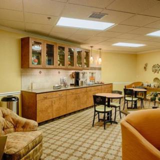 A cozy break room featuring a kitchenette with a coffee station, tables, and seating arrangements.