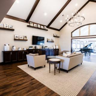 A modern and spacious living room with elegant furniture, a chandelier, and a grand piano.