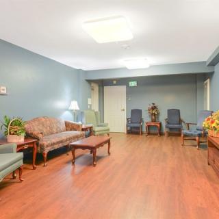 A cozy living room with wooden flooring, comfortable seating, and decorative plants.