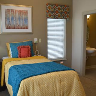 A vibrant and cozy bedroom featuring colorful bedding and a well-decorated wall.