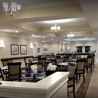 A stylish and elegant restaurant interior with neatly arranged tables and chairs, illuminated by chandeliers.
