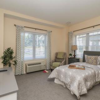 A cozy and well-lit bedroom featuring a comfortable bed, stylish furniture, and natural light from the windows.