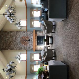A spacious lobby featuring elegant chandeliers, a central stone fireplace, and comfortable seating arrangements.