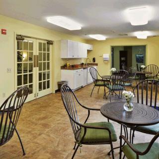 A cozy cafe interior with tables, chairs, and a small kitchenette area.