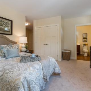 A cozy bedroom with elegant decor featuring a bed, bedside lamp, and an adjacent bathroom.