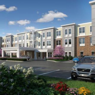 A modern residential building with well-maintained landscaping and a parking lot featuring several cars.