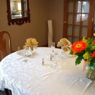 A well-set dining table adorned with flowers and folded napkins in a cozy indoor setting.