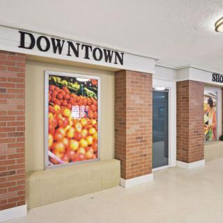 Interior view of a supermarket section with displayed fruits and brick walls.