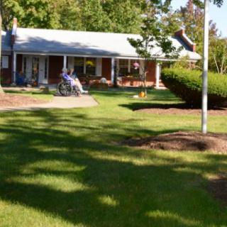 A suburban house with a well-maintained lawn, a motorcycle parked in the driveway, and a flagpole in the yard.