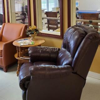 A cozy living room setup featuring a recliner and an orange chair with a small wooden table.