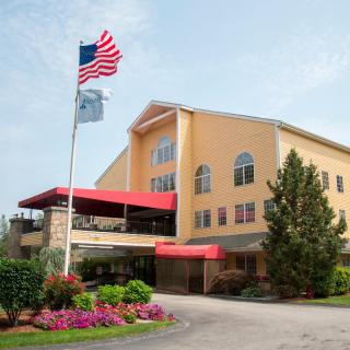A welcoming hotel entrance with landscaped gardens and flags flying.