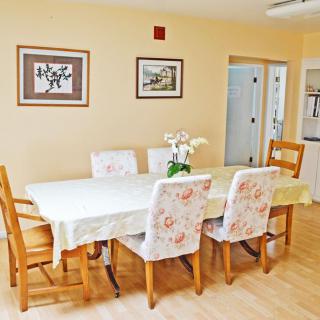 A bright dining room featuring a large table with floral-patterned chairs and wall art.