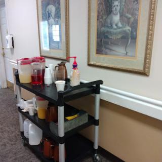 A beverage cart placed in a hallway, featuring various drinks and decorative artwork on the walls.